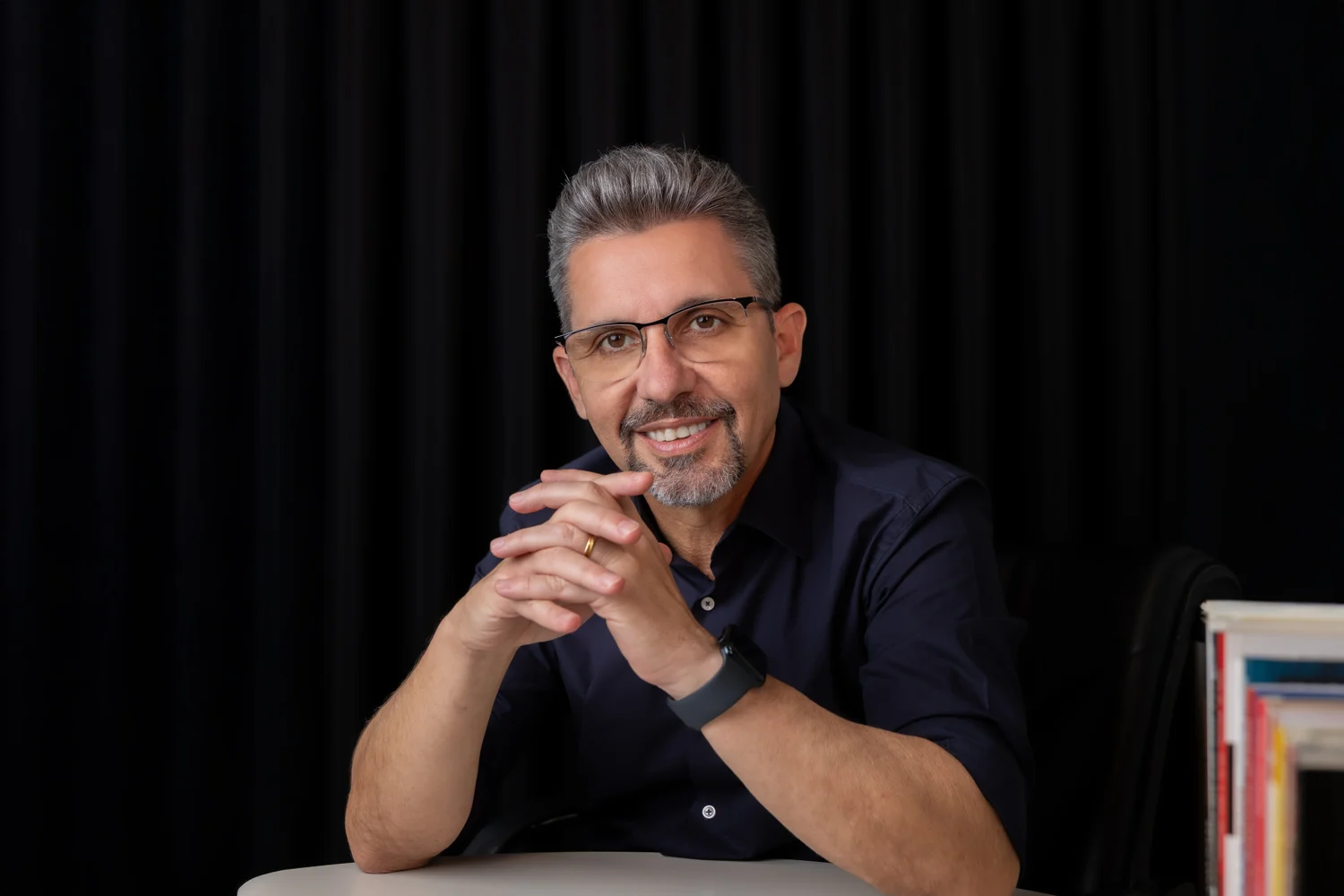 Roberto Vilela sentado à mesa, ao lado de livros